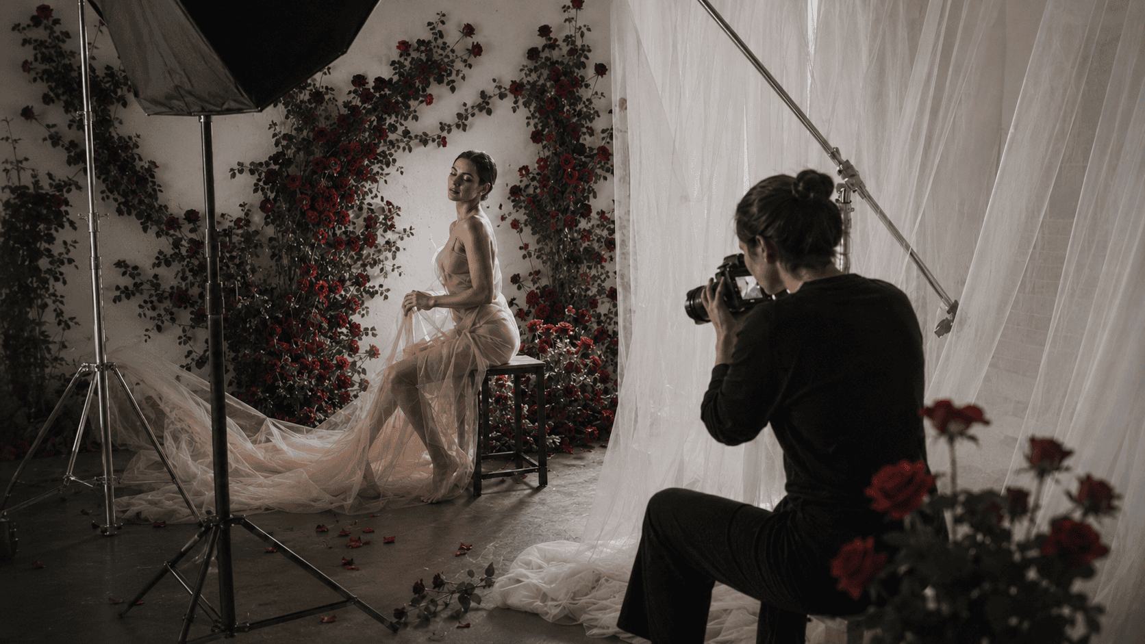 Fotógrafa a fotografar uma mulher num cenário de rosas e tule